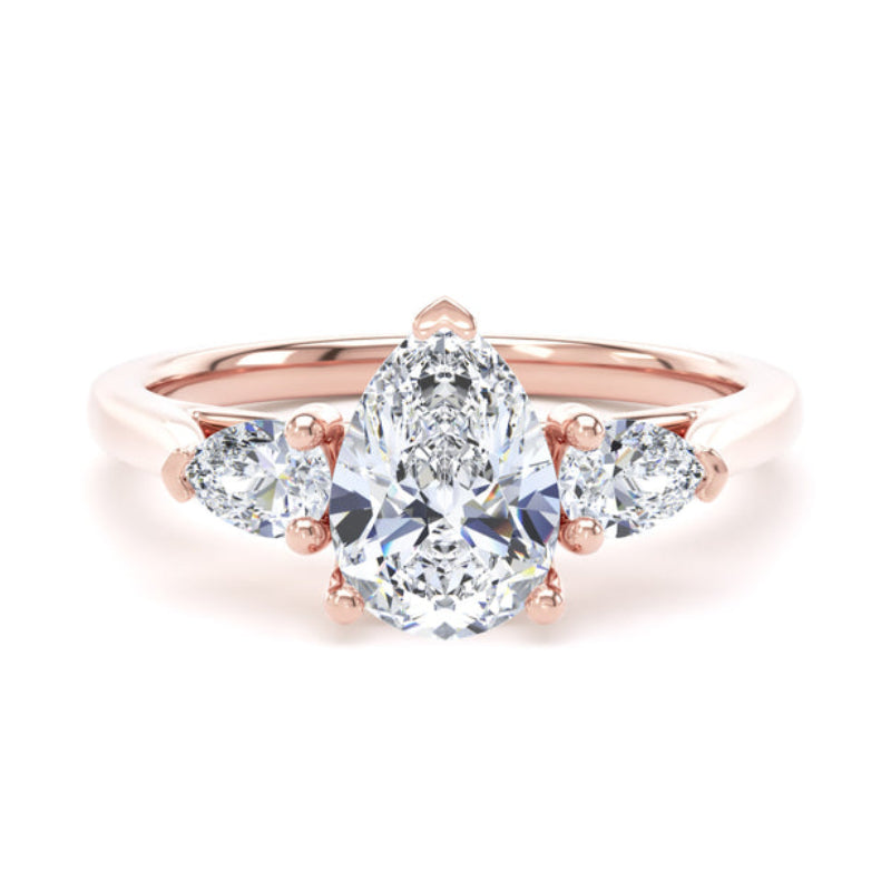 A rose gold ring featuring a pear-cut center stone flanked by two smaller marquise-cut stones on each side, set against a clean white background.