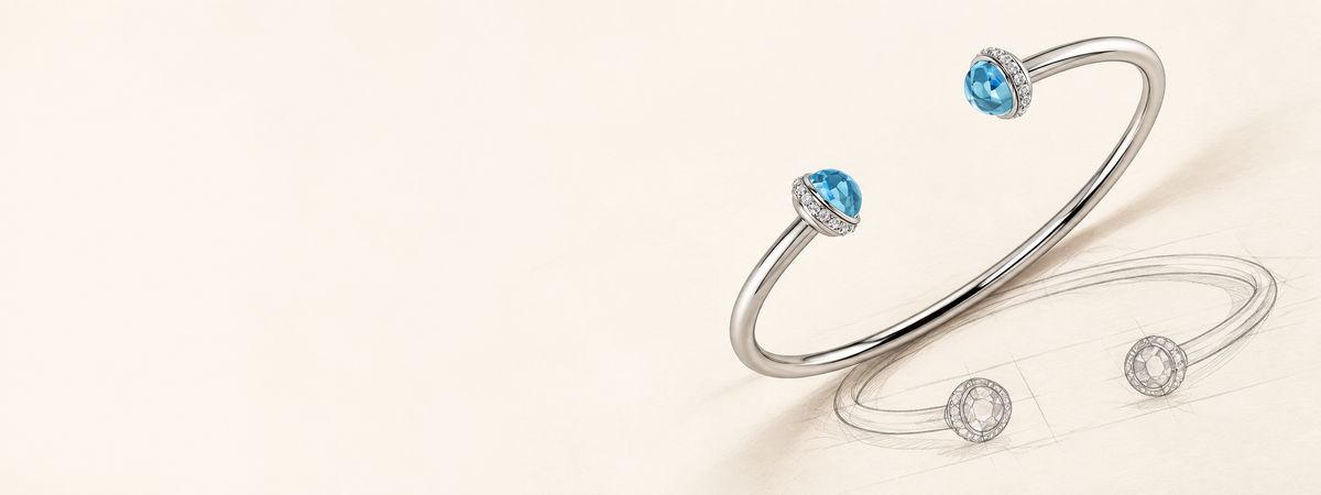 A polished silver-tone open cuff bracelet with two blue gemstone accents and small clear stones, shown on a clean off-white background.