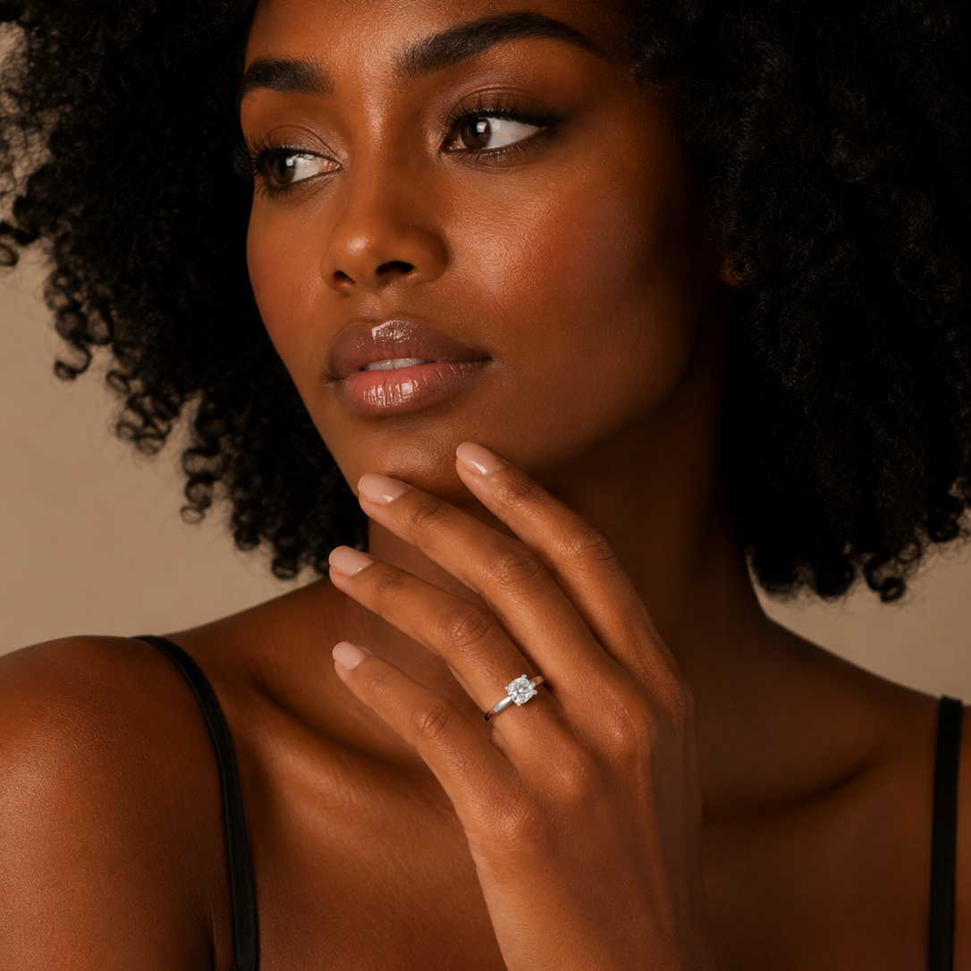 Woman with a ring on her finger, wearing a black top against a neutral background