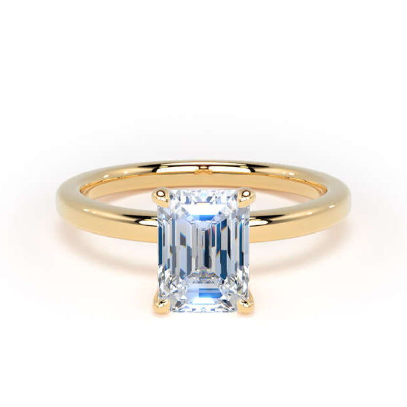 A yellow gold ring featuring a rectangular emerald-cut light blue gemstone in a four-prong setting, shown against a plain white background.