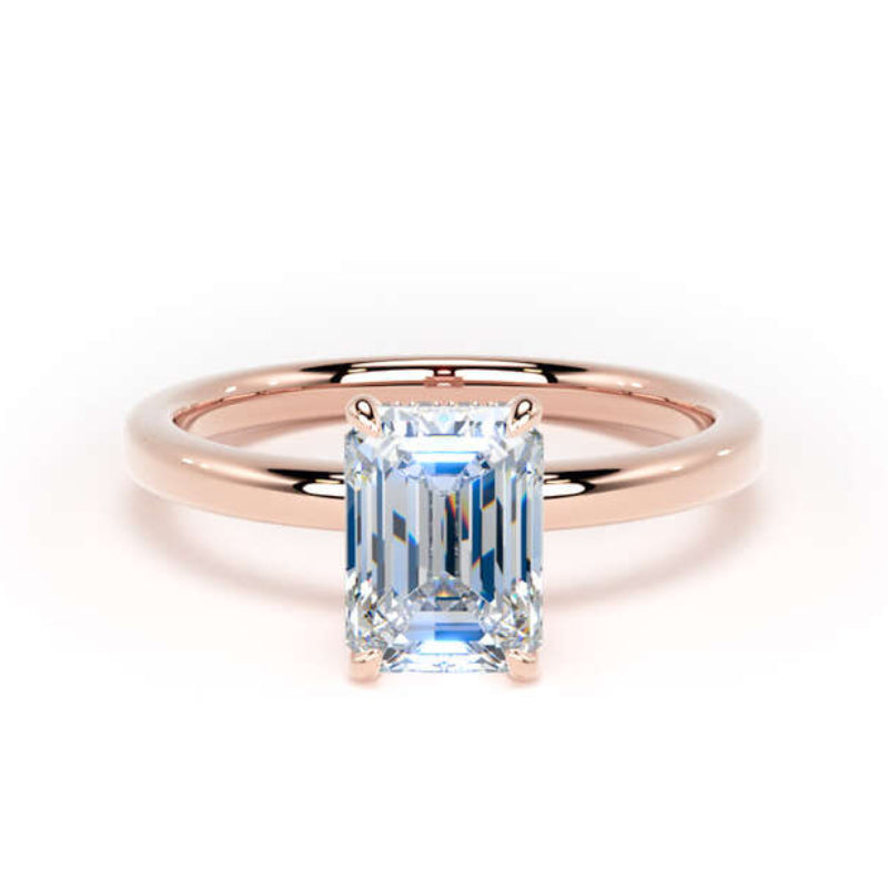 An emerald-cut blue sapphire engagement ring in a polished rose gold band, centered on a clean white background.