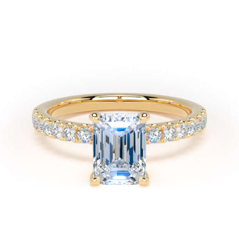 A yellow gold ring featuring a large emerald-cut light blue center stone and a pavé-set diamond band, shown on a clean white background.