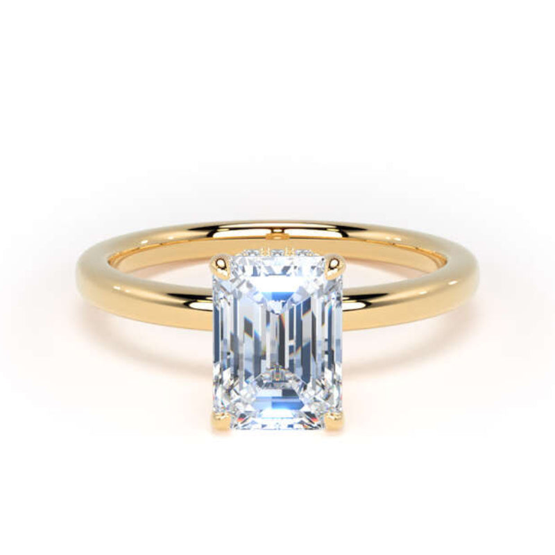 An emerald-cut diamond ring set on a polished yellow gold band, photographed against a seamless white background.