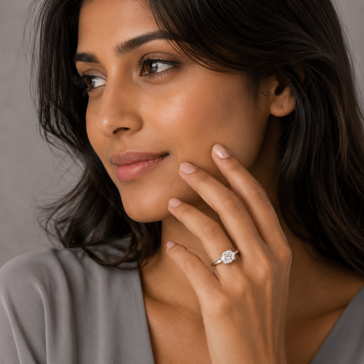 Woman wearing a diamond ring on her finger against a neutral background