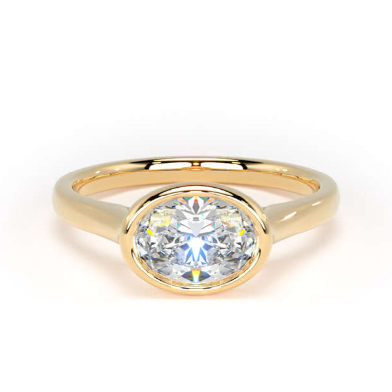 A yellow gold oval solitaire ring featuring a round brilliant-cut clear gemstone in a bezel setting, shown on a plain white background.