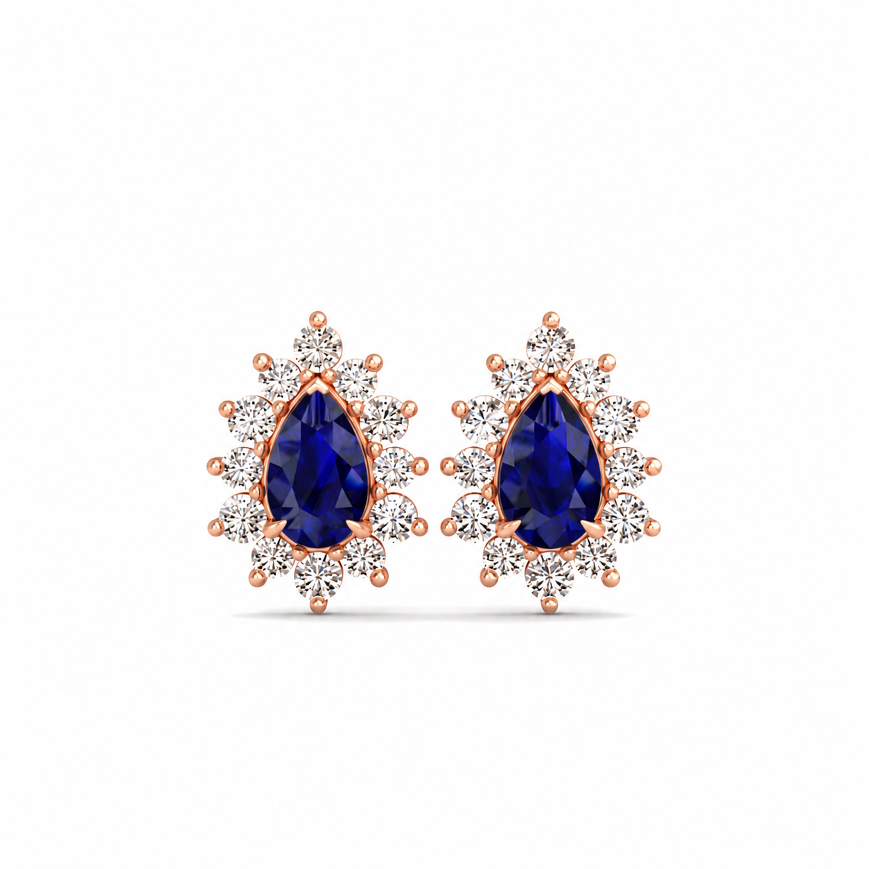 A pair of rose gold stud earrings featuring pear-shaped deep blue sapphire centers surrounded by clear round-cut cubic zirconia halos, set against a plain white background.