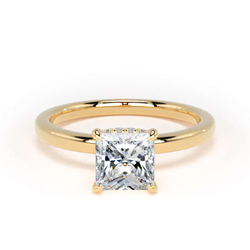 A yellow gold solitaire ring featuring a large princess-cut clear gemstone in a four-prong setting, shown on a clean white background.