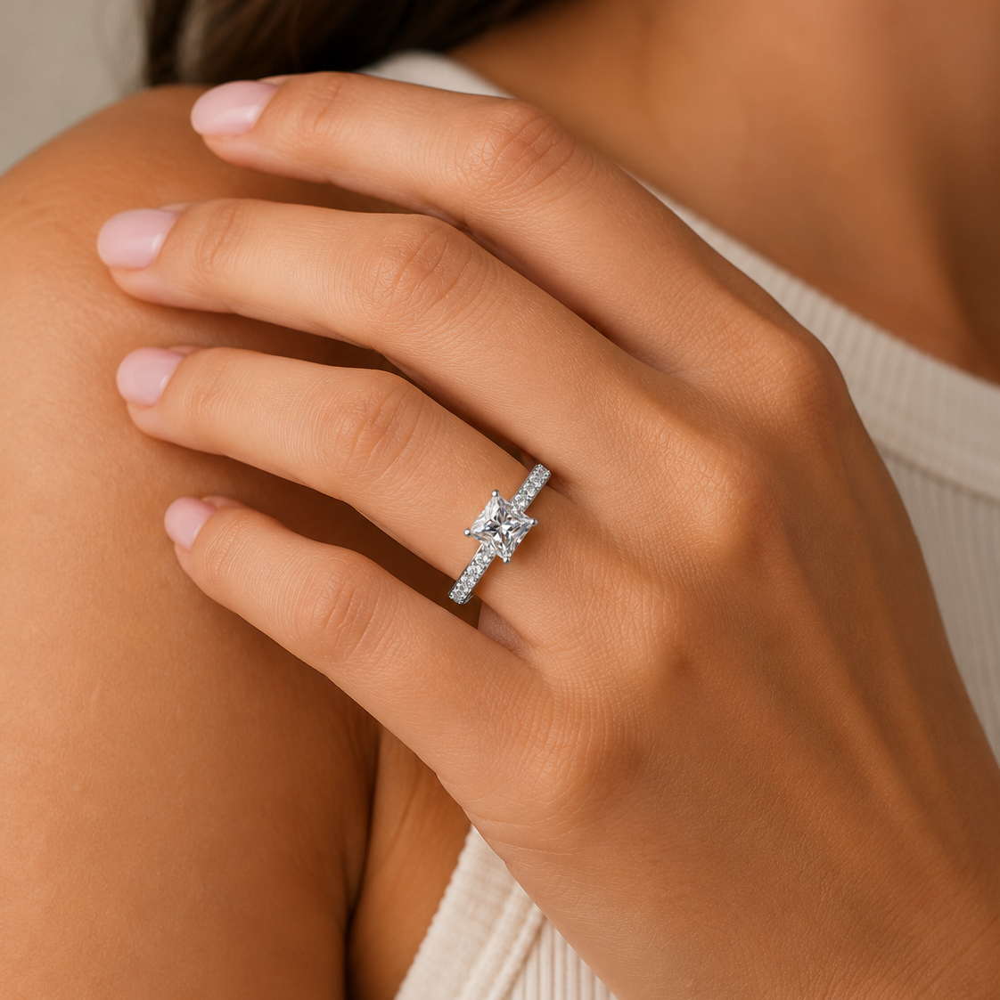 Close-up of a hand wearing a diamond ring on a neutral background