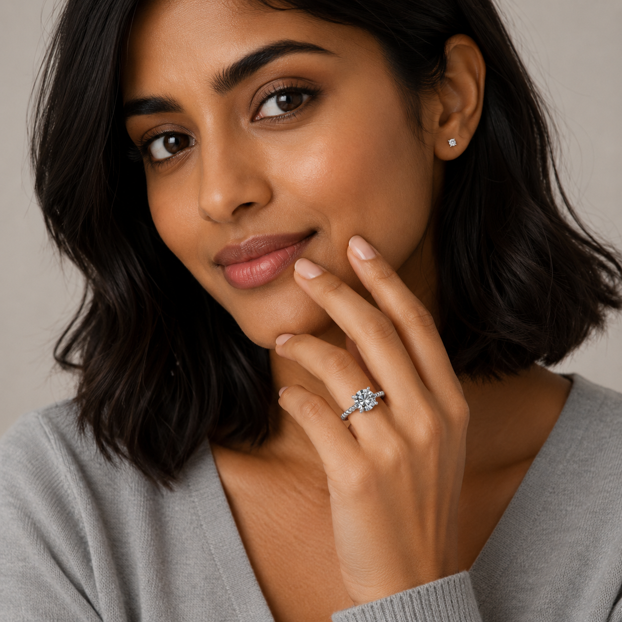 Woman wearing a diamond ring on her finger against a neutral background