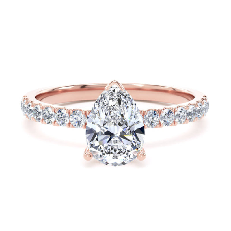 A rose gold engagement ring featuring a pear-cut center diamond and a pavé band with small round diamonds, set against a plain white background.