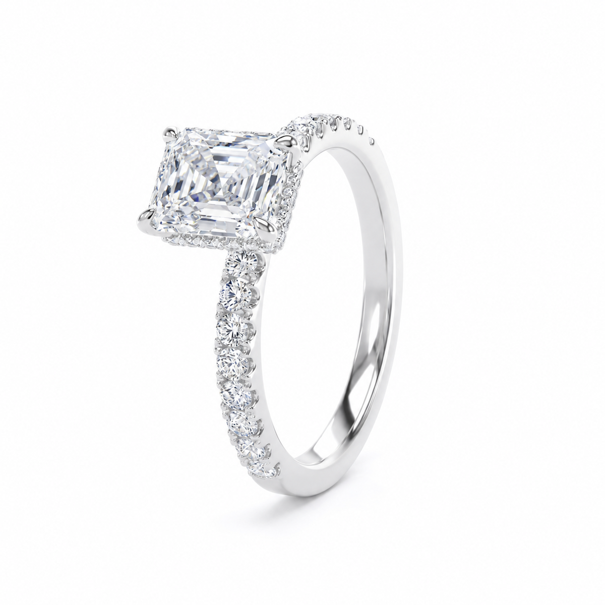 A radiant-cut diamond engagement ring in a polished silver-colored metal band, featuring a halo of small diamonds along the shank, set against a clean white background.