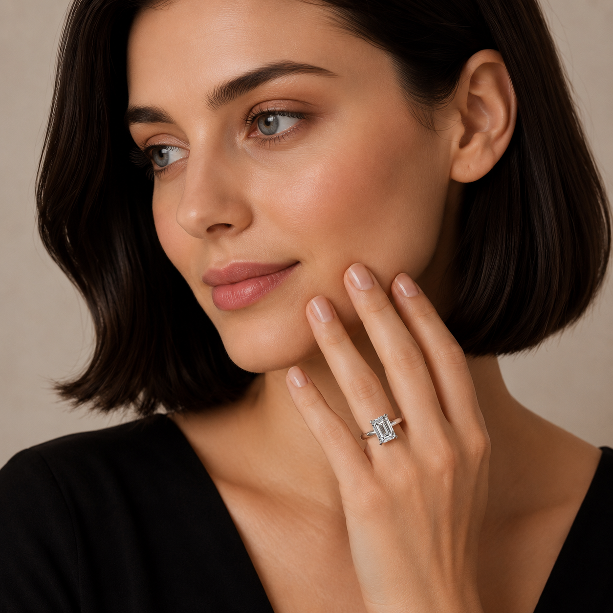 Woman wearing a diamond ring on her finger against a neutral background