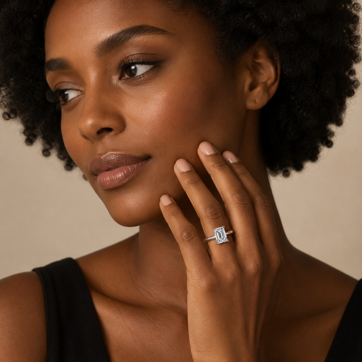Woman wearing a diamond ring on her finger against a neutral background