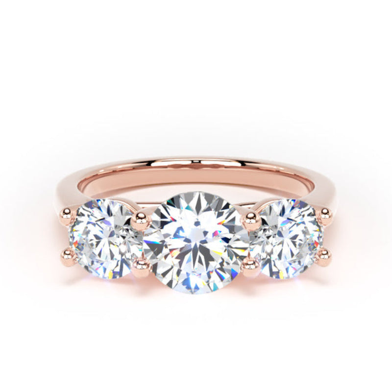 A three-stone diamond engagement ring in rose gold, featuring a round center diamond flanked by two round side diamonds on a polished rose gold band, set against a clean white background.