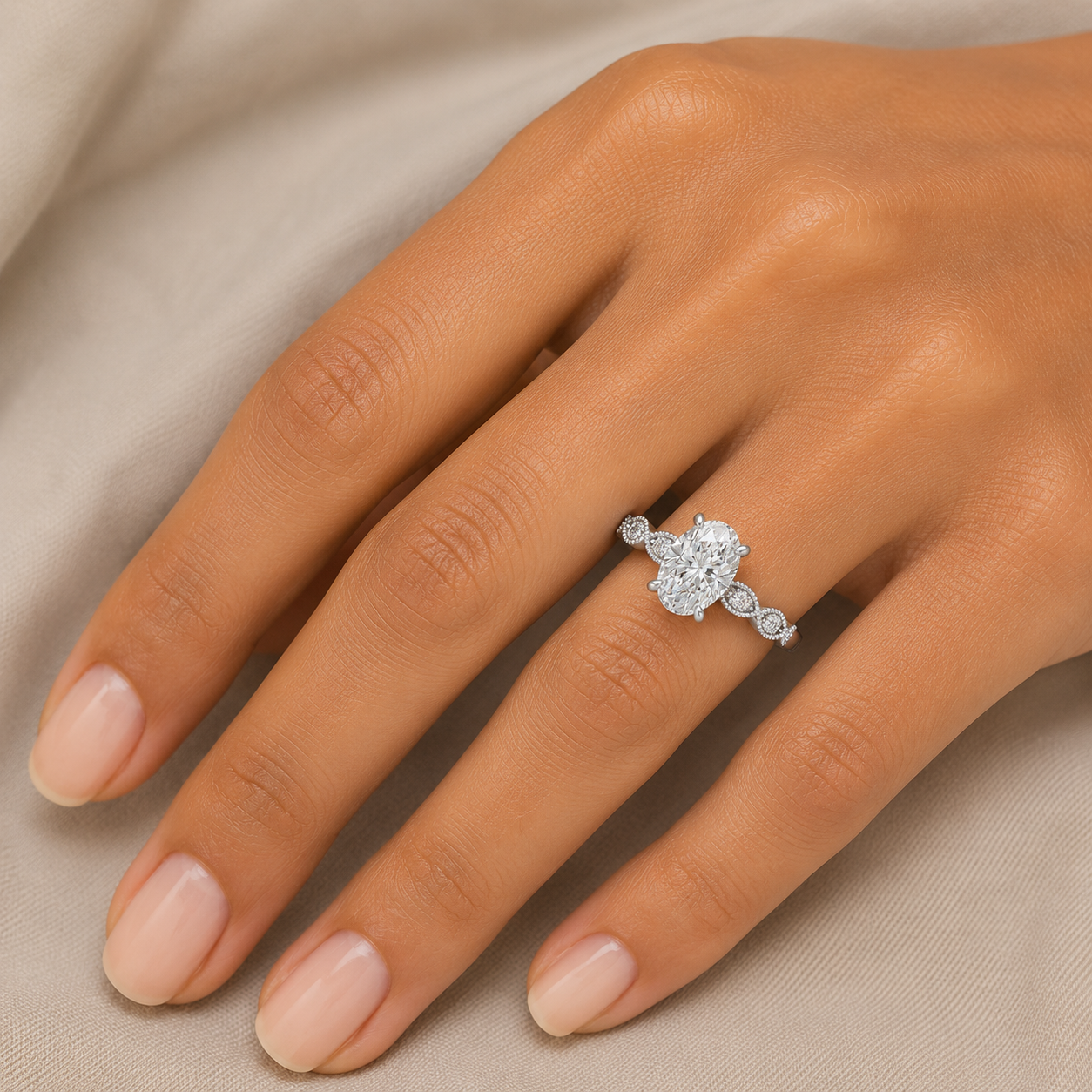 A close-up of a hand wearing a silver-toned ring with a large round-cut center stone and smaller accent stones along the band, set against a soft beige fabric background.