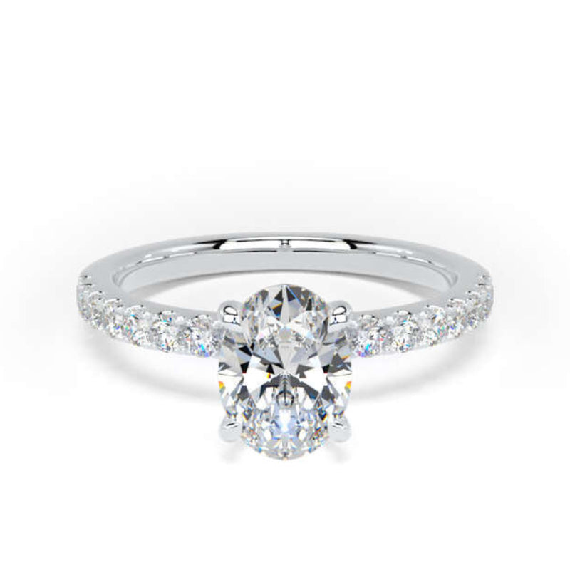 A silver engagement ring featuring a round-cut center stone and a pavé band with small round stones, set against a plain white background.