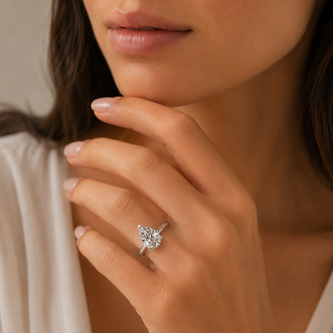 Close-up of a hand wearing a diamond ring with a neutral background