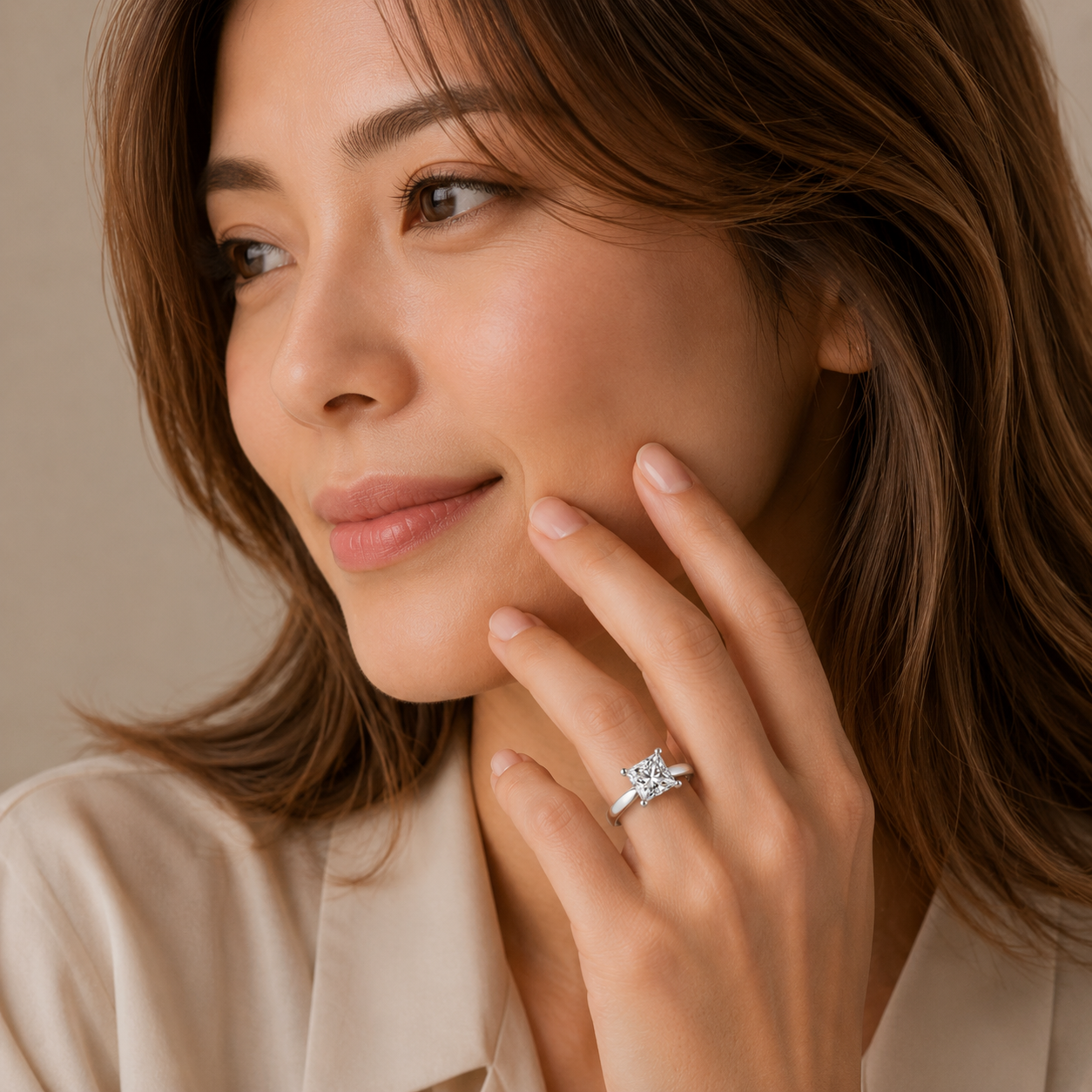 Woman wearing a diamond ring on her finger against a neutral background