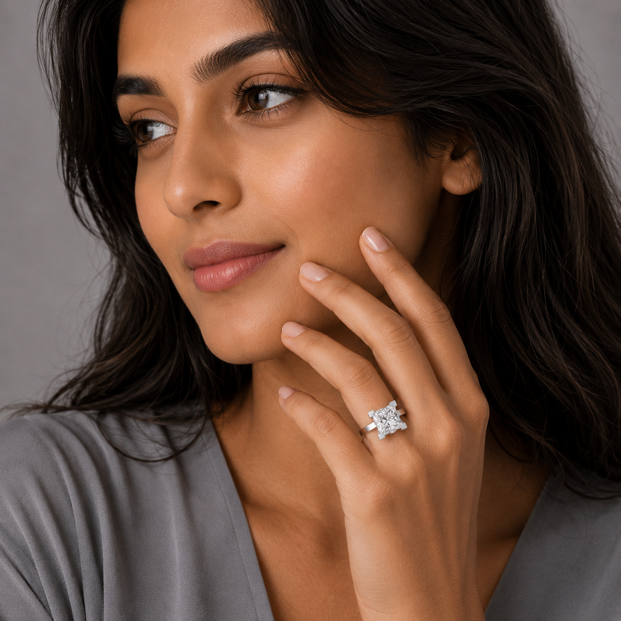 Woman wearing a diamond ring on her finger against a neutral background