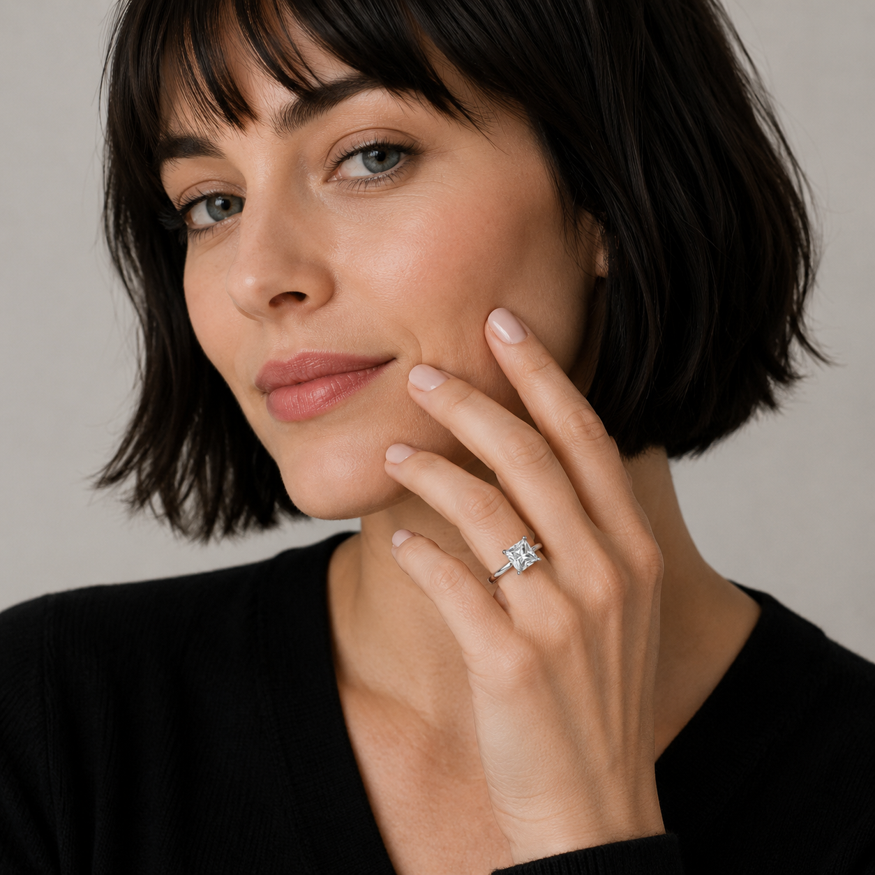 Woman wearing a diamond ring on her finger against a neutral background