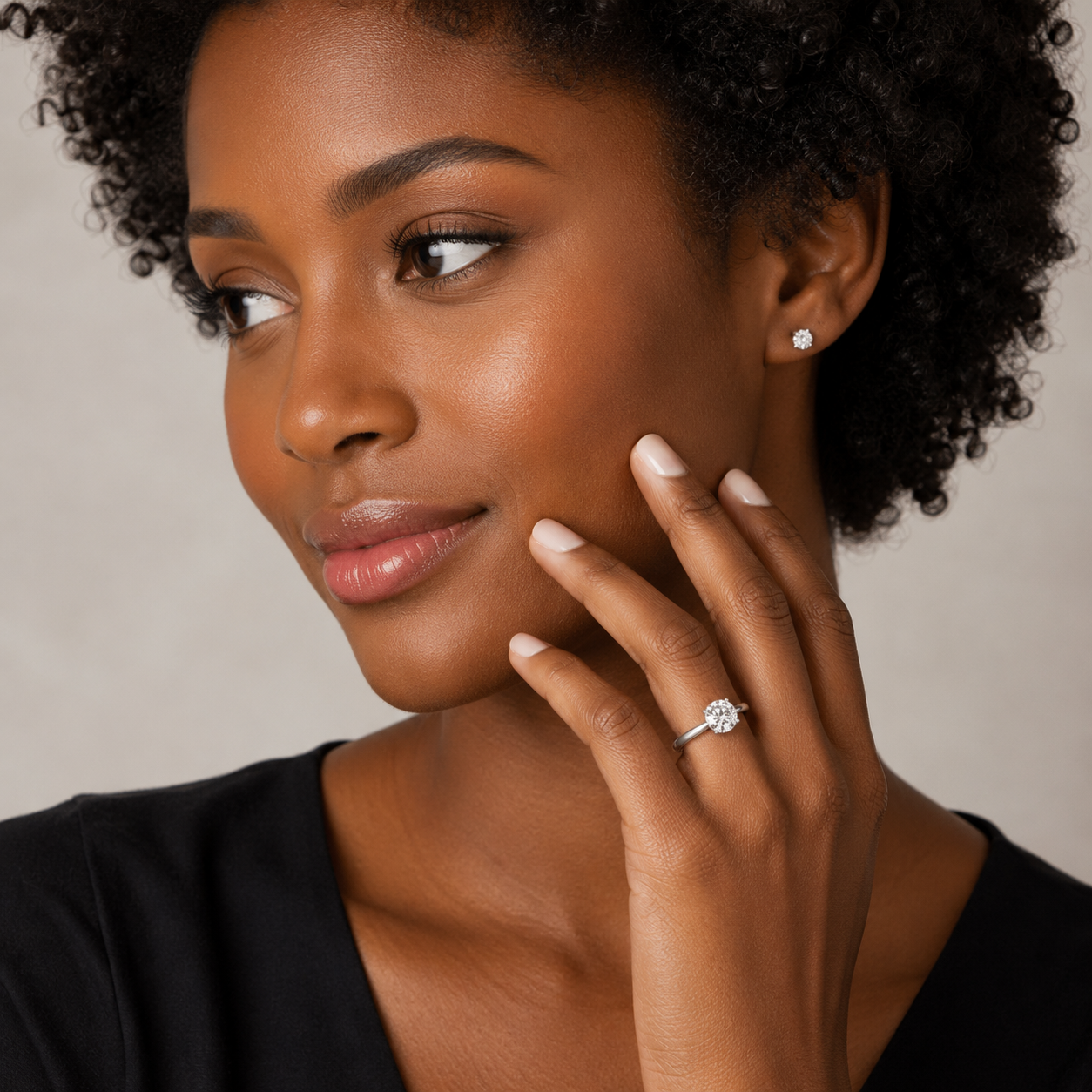 Woman wearing a diamond ring on her finger against a neutral background