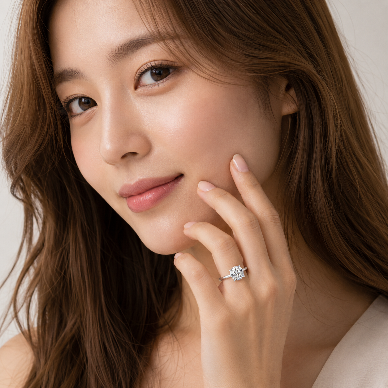 Woman wearing a diamond ring on her finger, touching her face.