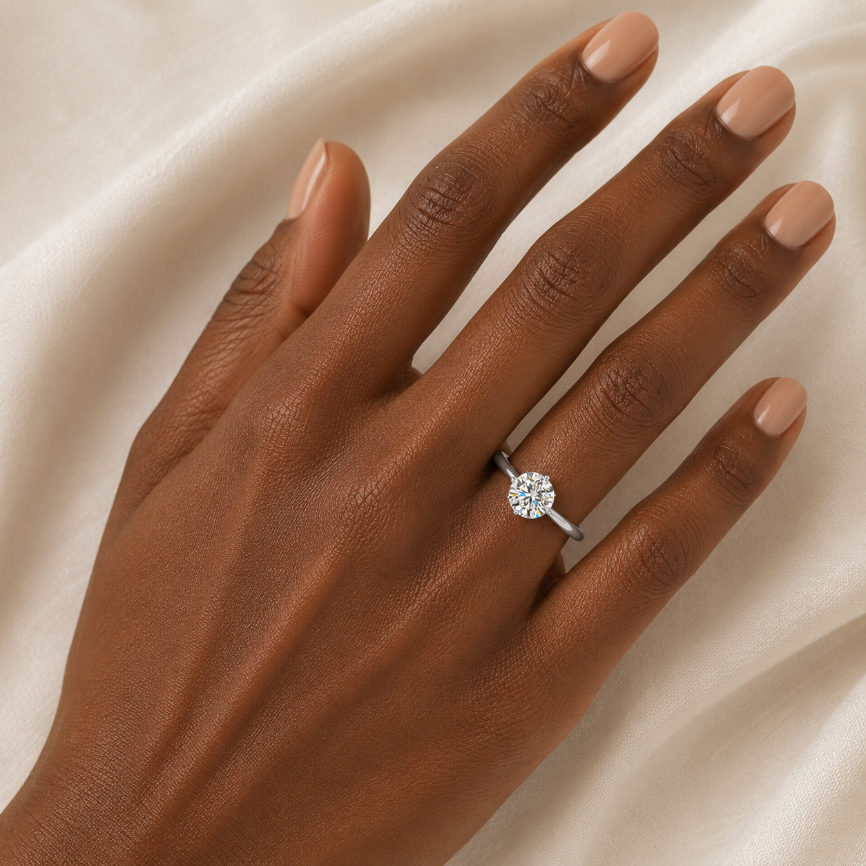 Hand wearing a diamond ring on a beige fabric background