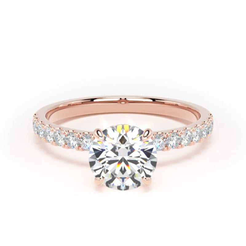 A rose gold engagement ring featuring a round-cut center diamond and a pavé band with small diamonds, set against a plain white background.